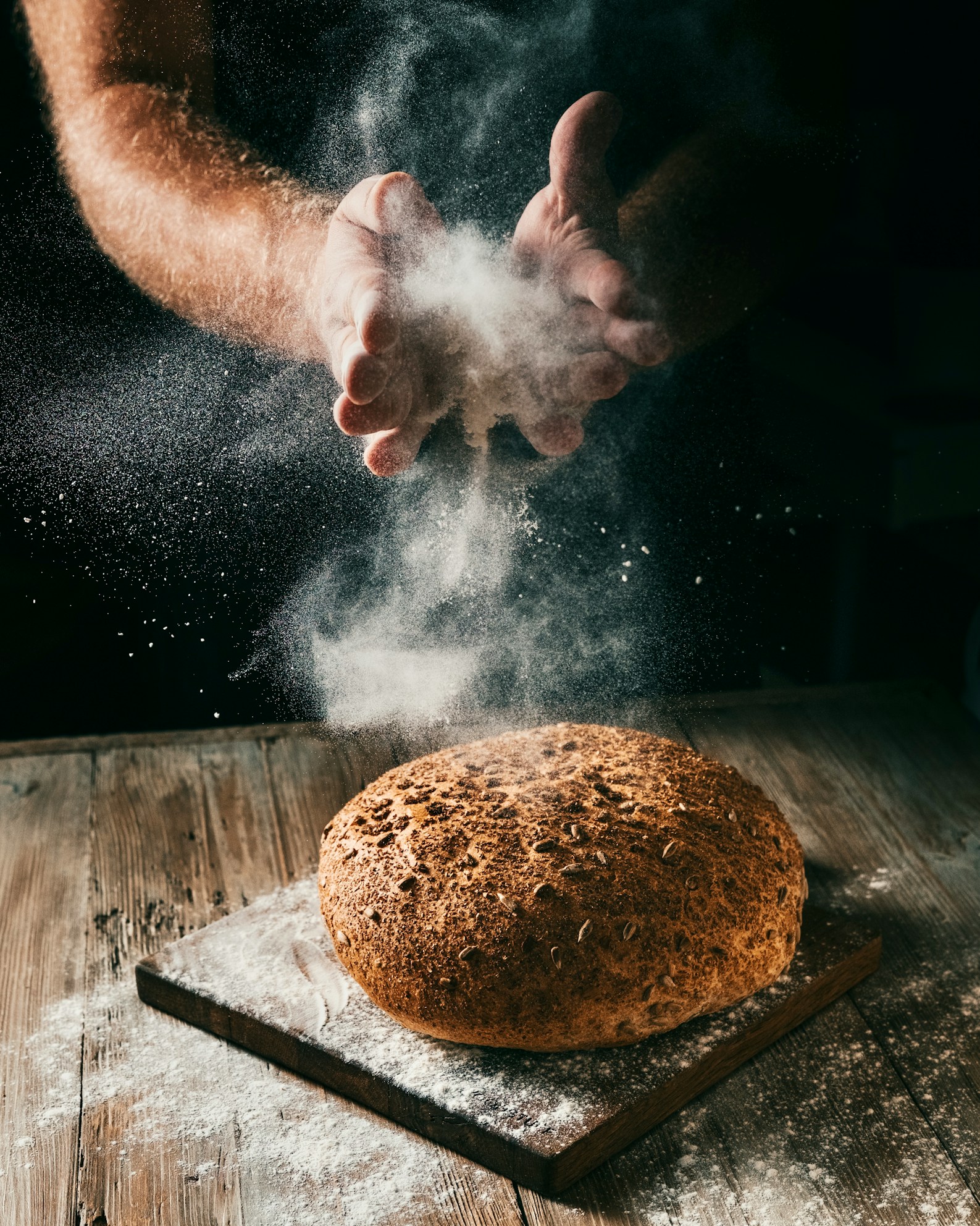 A baker dusting flour over fresh bread